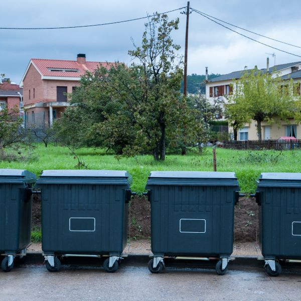 Row of dumpsters lined up in a DC Washington neighborhood, representing junk removal vs dumpster rental options.