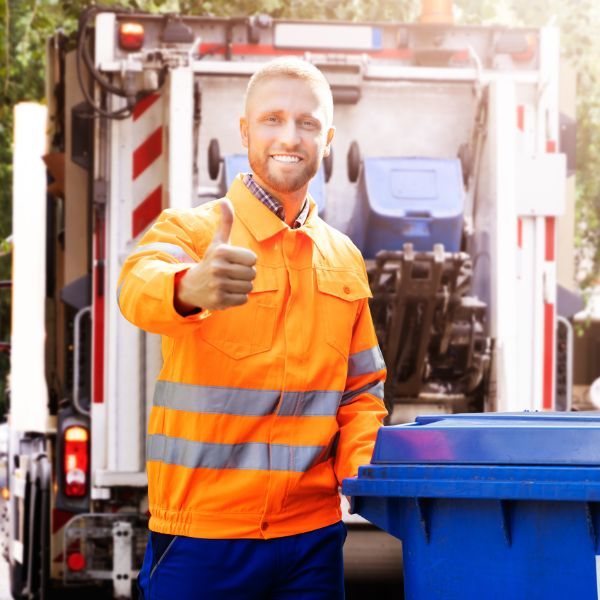 Smiling sanitation worker giving thumbs up next to a blue bin and garbage truck, symbolizing the solution to the cost of clutter in DC, Washington.